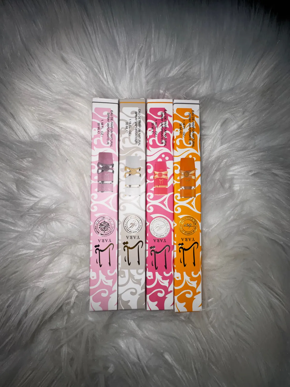 Four patterned perfume rollerballs on white fur