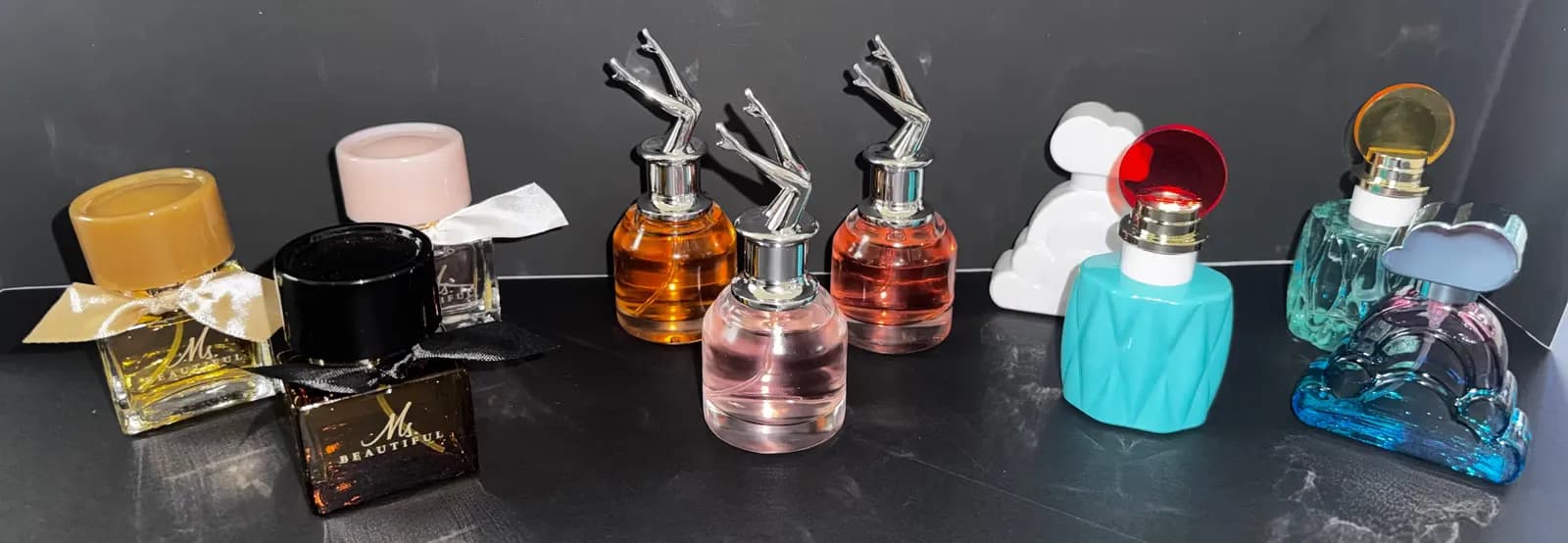 Mini designer perfume bottles lined up on a dark surface