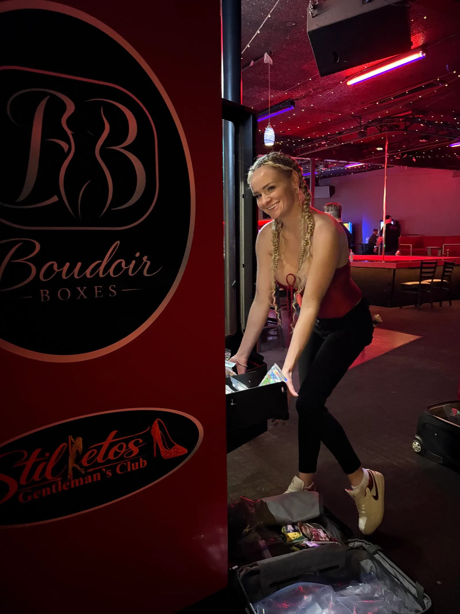 Restocking a Boudoir Boxes machine beside the Boudoir Boxes and Stilettos branding